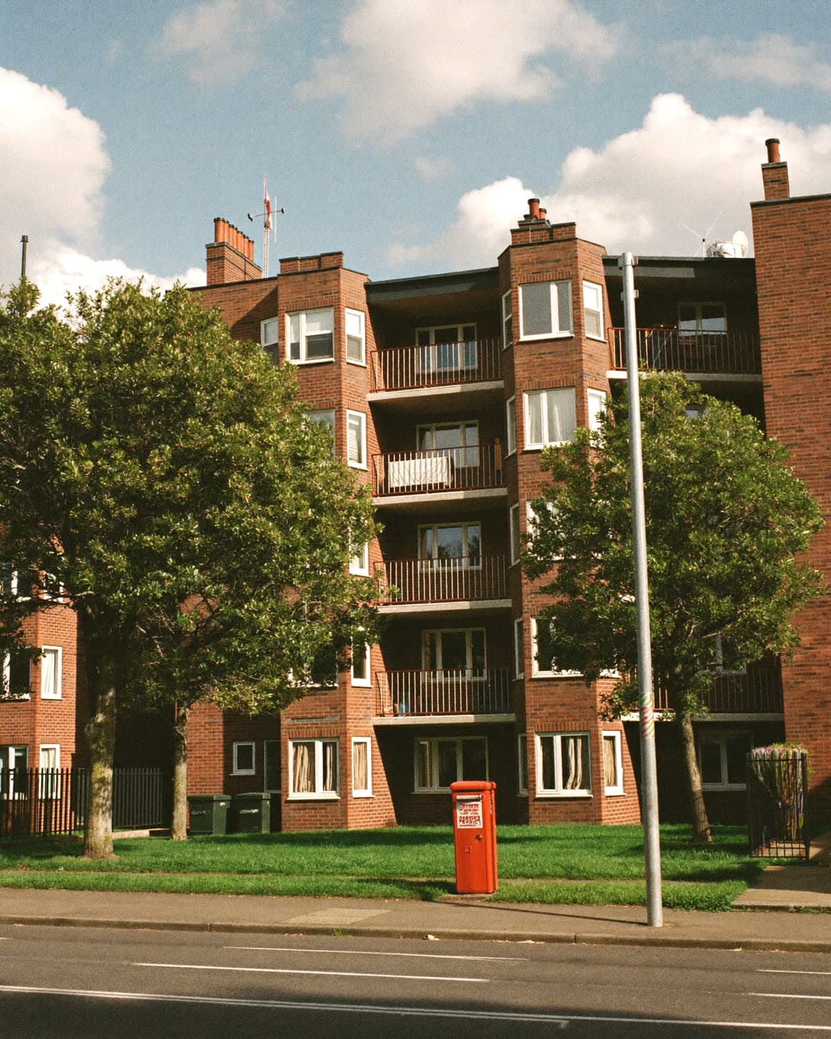 A post-war red brick council housing block on a residential street.
