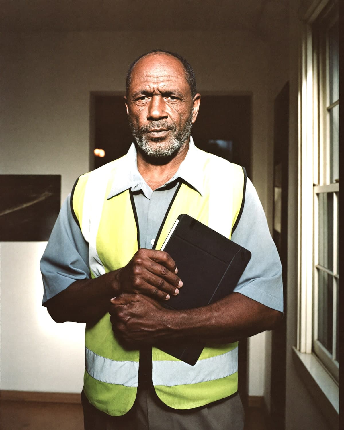 Surveyor in a hi-vis vest holding a rugged tablet inside a property.